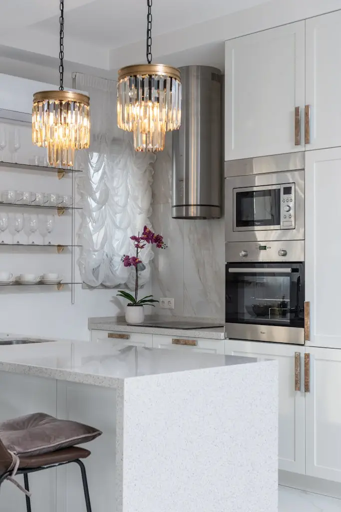 Bright modern kitchen interior with elegant lighting and stainless steel appliances.